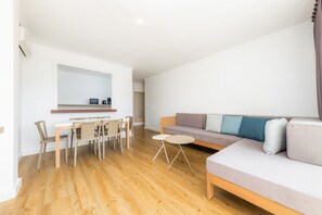 A modern living room with a sofa, a dining table, and chairs.