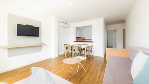 Ein modernes Wohnzimmer mit Flachbildfernseher, Essbereich mit Stühlen und Tisch sowie einer Couch.