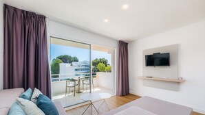 Ein modernes Wohnzimmer mit einer Couch, einem an der Wand befestigten Fernseher und einem Balkon mit Tisch und Stühlen.