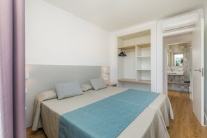 A bedroom with a bed, bedside tables, a wardrobe, and an open door to a bathroom.