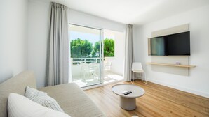 A modern living room with a sofa, a round coffee table, a TV mounted on the wall, and a balcony with outdoor furniture. - Apartment 'Apartament Massanet 1c' with Balcony, Wi-Fi and Air Conditioning (Canyamel)