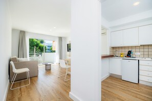 A modern apartment with a living area, kitchen, and a balcony with a view.