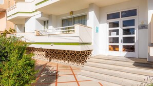 Un edificio de varios pisos con fachada blanca, un balcón y una puerta que dice 'APOT. MANSANET'.