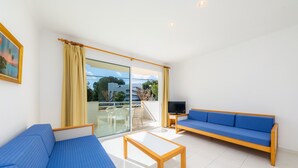 Una sala de estar moderna con sofá, mesa, televisor y balcón con puertas de vidrio.