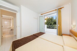 A hotel room with a bed, a bathroom, and a balcony with a view.