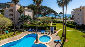 Una piscina con varias secciones, sillas de descanso y vista al mar.