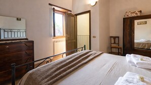 A bedroom with a bed, dresser, mirror, and a door leading to another room.