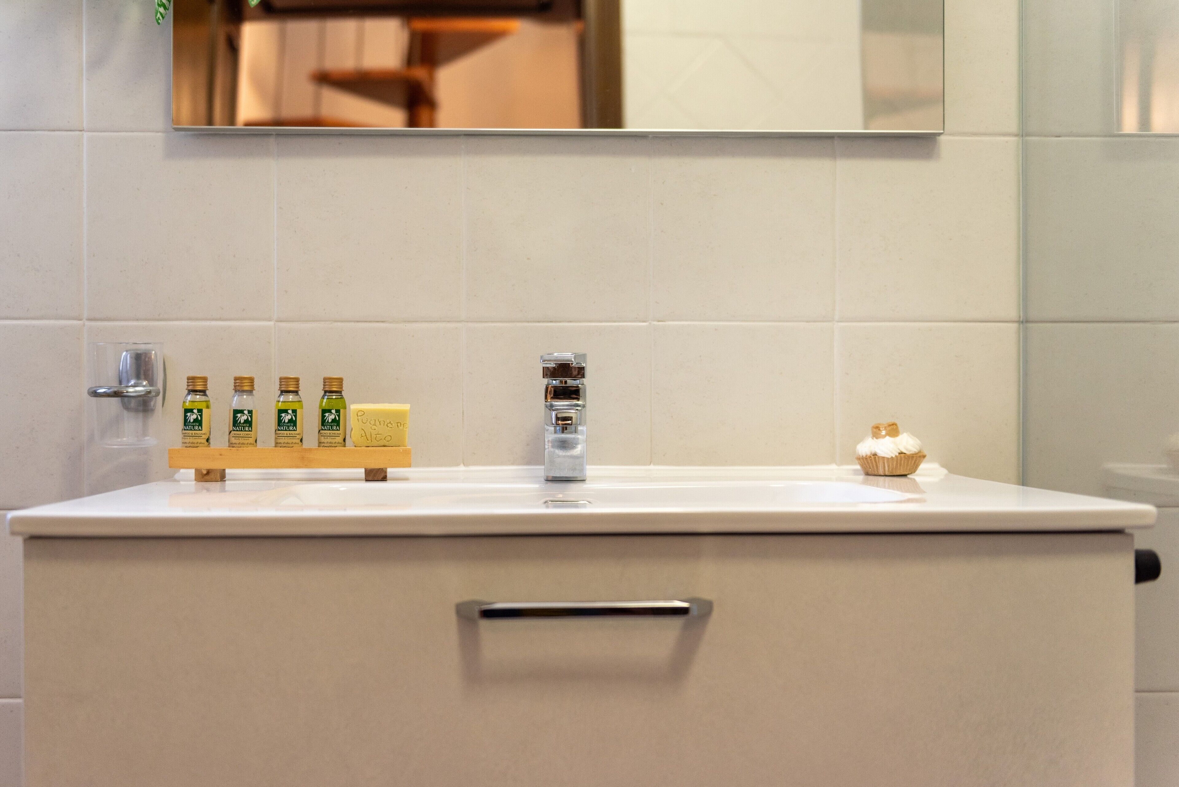 A bathroom with a sink, mirror, and toiletries.