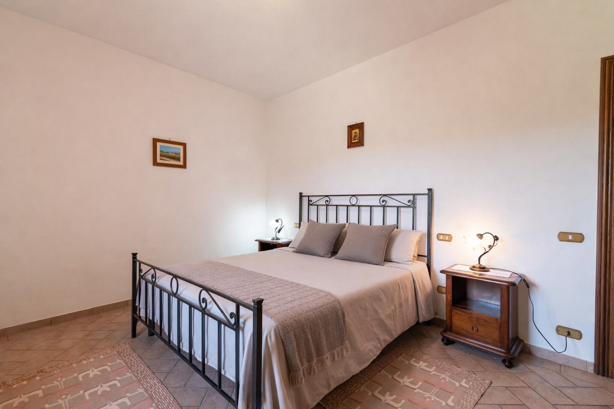 Une chambre à coucher comprenant un lit, des tables de chevet, une commode et une lampe fixée au mur.