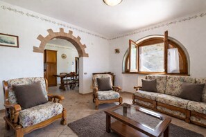 Un salon comprenant un canapé, deux fauteuils, une table basse et un coin repas avec une table et des chaises.