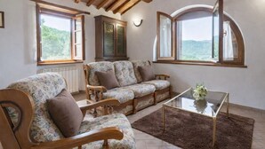 Ein gemütliches Wohnzimmer mit einer Sofagarnitur, einem Couchtisch und großen Fenstern mit Blick ins Freie.