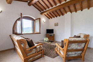 Una sala de estar con un sofá, un sillón y un mueble para televisor.
