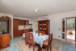 A dining area with a table set for four, wooden cabinets, and a view through a sliding glass door.
