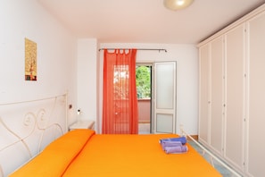 A bedroom with a bed, a nightstand, a wardrobe, and a window with a curtain.