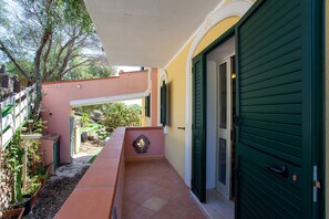Un espacio al aire libre cubierto con un banco, una puerta y una pared con un adorno decorativo.