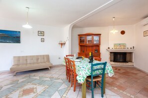 A dining area with a table set for four, a sofa, a wooden cabinet, and a fireplace.