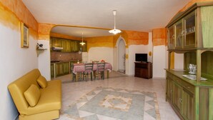 A living room with a sofa, dining table, chairs, a cabinet, and a television. - Apartment "Alloro" with Terraces & Wi-Fi (Sos Alinos)