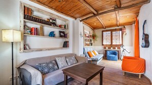 A cozy living room with a wooden ceiling, a sofa, a coffee table, and a bookshelf filled with books. - Holiday Home 'La Lechuga Azul' with Mountain View, Private Terrace and Wi-Fi (Guejar Sierra)