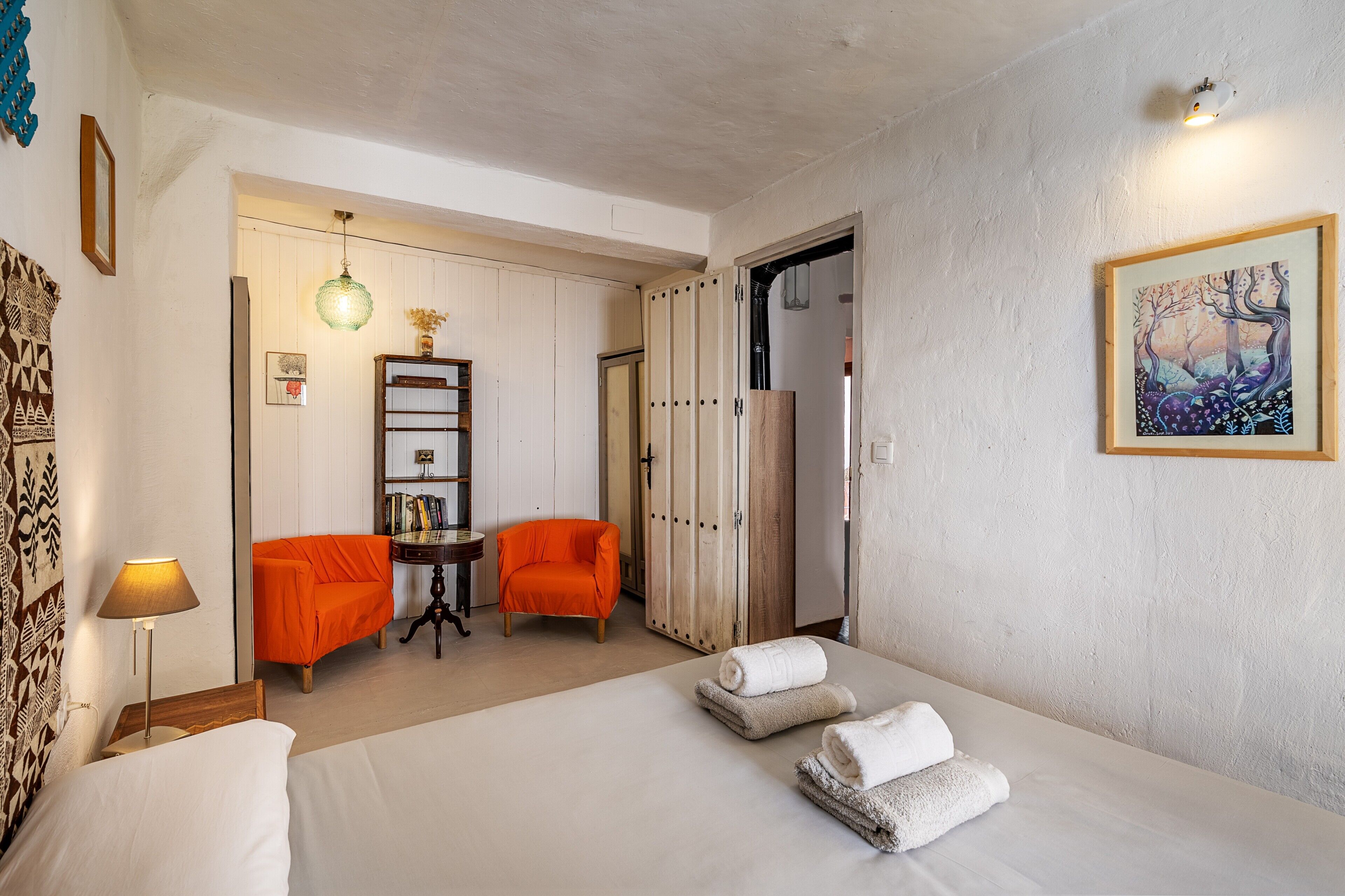 Une chambre d ’hôtel avec un lit, deux chaises, une table, une lampe et un tableau au mur.
