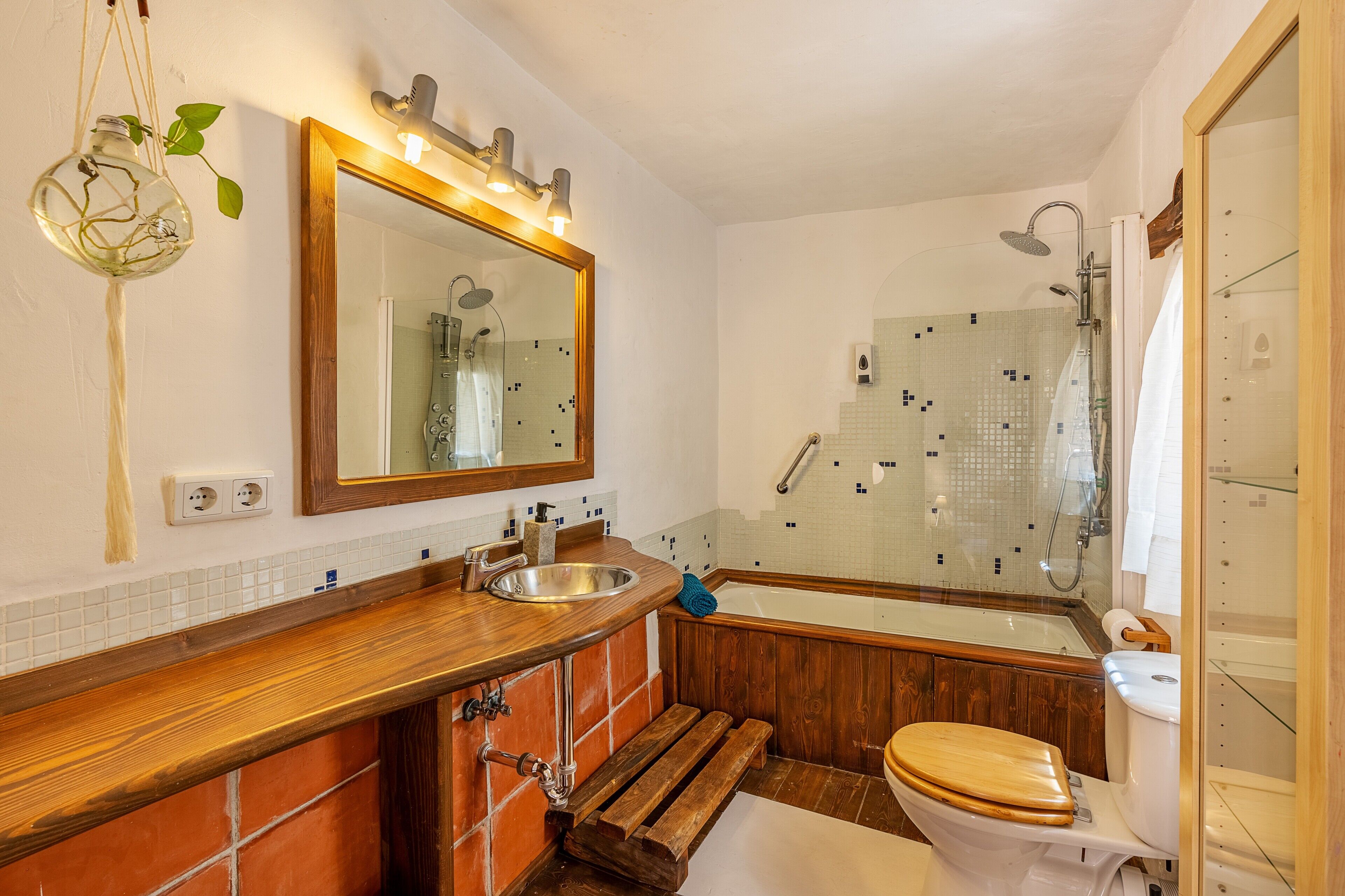 Un baño con tocador de madera, lavamanos, inodoro, bañera y ducha.