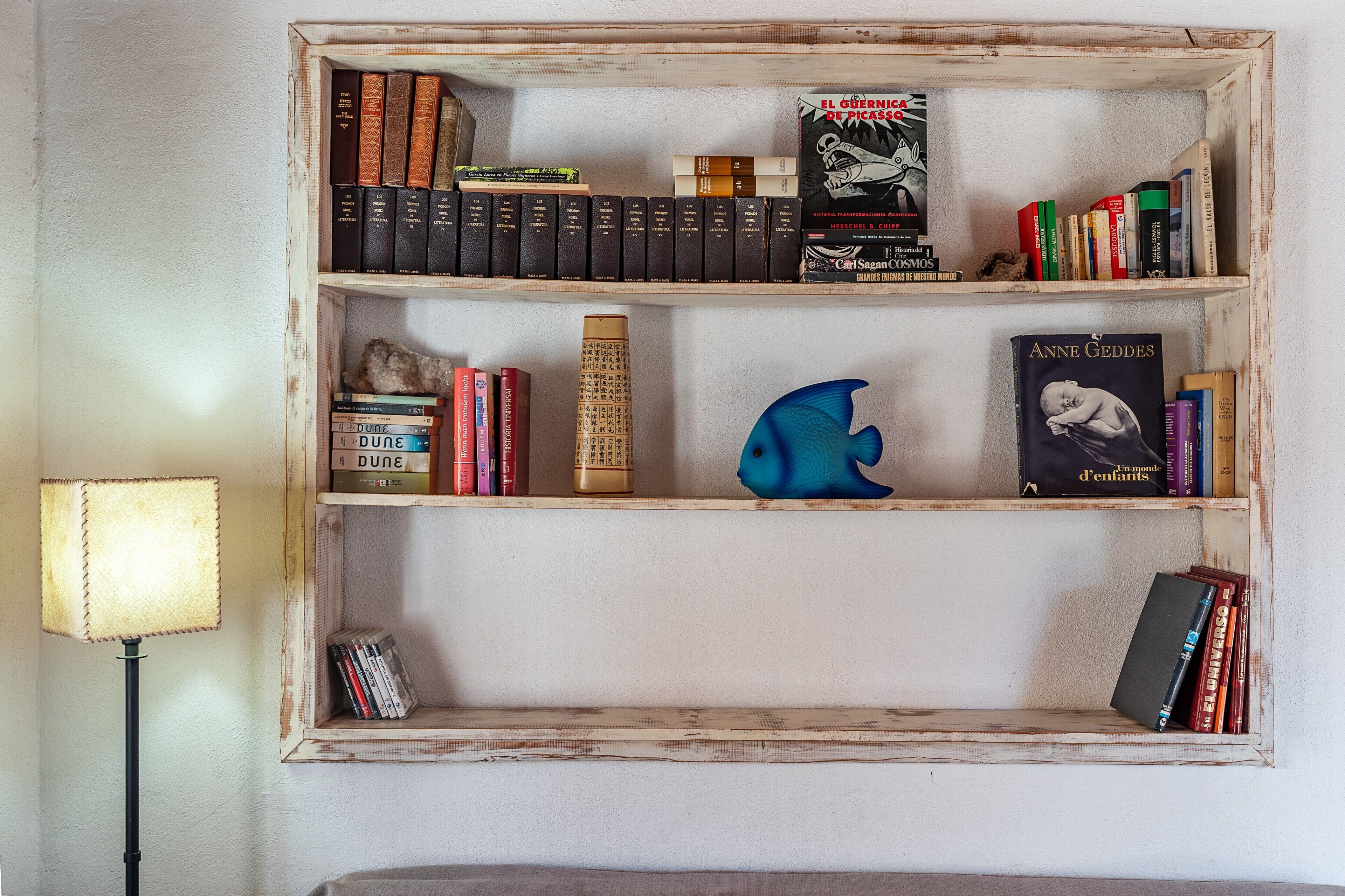 Une bibliothèque remplie de livres, un globe terrestre et une figurine de poisson bleue.
