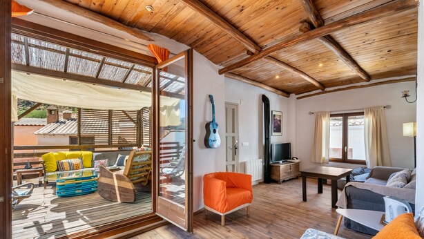 An open-plan living area with a wooden ceiling, a guitar, a sofa, and a dining table. - Holiday Home 'La Lechuga Azul' with Mountain View, Private Terrace and Wi-Fi (Guejar Sierra)