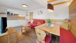 Een modern interieur met een houten eettafel, een rode bank en een televisie op een houten dressoir.