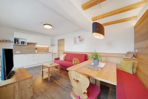 A modern interior with a wooden dining table, red sofa, and a television on a wooden stand. - Apartment 'Nelkenstein Frühling' with Mountain View, Shared Pool and Wi-Fi (Scena)