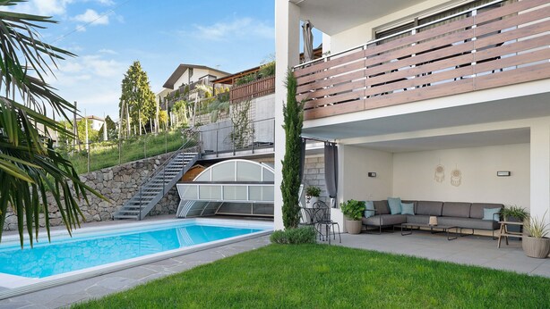 Een modern huis met een zwembad, een overdekt terras en een trap naar een tweede verdieping.