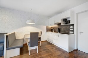 A compact kitchen with white cabinets, a built-in stove, and a coffee maker.
