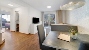 Ein modernes Wohnzimmer mit Esstisch, einer Couch, einem Fernseher und Bergblick.