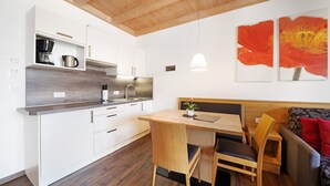 Moderni keittiö, jossa on valkoiset kaapit, puinen ruokapöytä ja penkki.