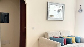 A living room with a beige sofa, a framed mirror, and a tiled floor.
