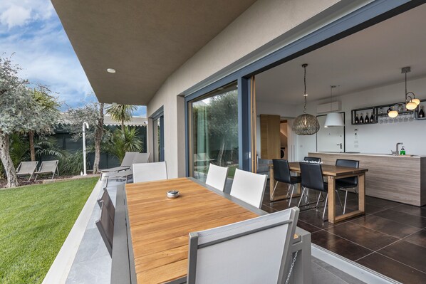 A modern kitchen with a dining area, large windows, and a view of the outdoors.
