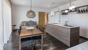 Una cucina moderna con un tavolo da pranzo in legno, un'isola integrata con lavello e una cantina a muro.