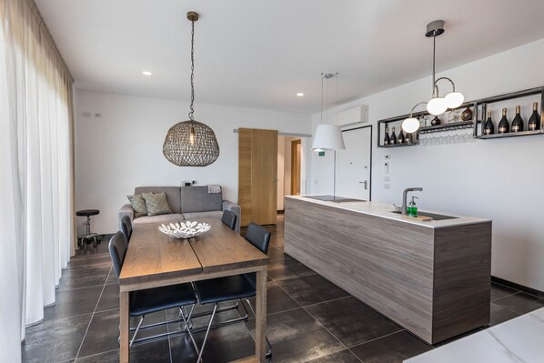 Eine moderne Küche mit einem Holzespeisetisch, einer integrierten Kochinsel mit Spüle und einem Weinschrank darüber.
