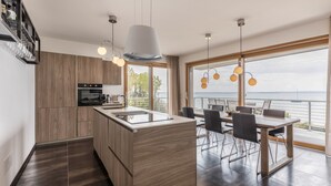 Eine moderne Küche mit Holzausstattung, einer zentralen Kochinsel und einem Essbereich mit Meerblick.