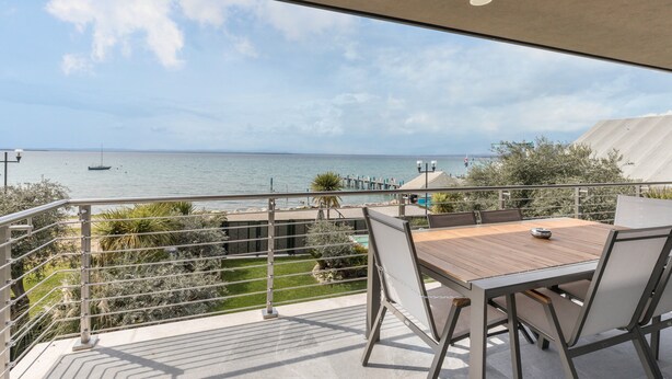Ein Balkon mit Meerblick, einem Tisch mit Stühlen und einem Geländer.