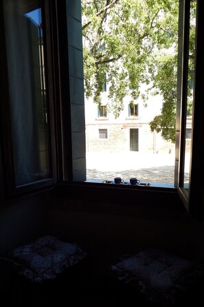 A room with a large window, a view of a courtyard, and a window sill with cups. - Apartment 'Zen' with Sea View, Wi-Fi and Air Conditioning (Venice)