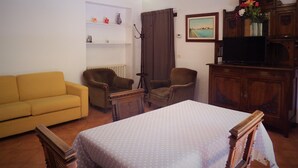 A room with a bed, a sofa, two armchairs, a television, a cabinet, and a painting on the wall. - Apartment 'Zen' with Sea View, Wi-Fi and Air Conditioning (Venice)