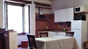 A kitchen with a stove, microwave, and refrigerator, wooden beams, and a window. - Apartment 'Zen' with Sea View, Wi-Fi and Air Conditioning (Venice)