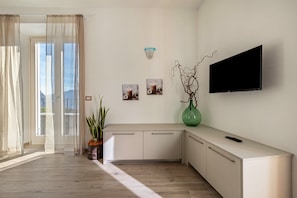 Un salon moderne avec un téléviseur, une plante et une fenêtre avec des rideaux.