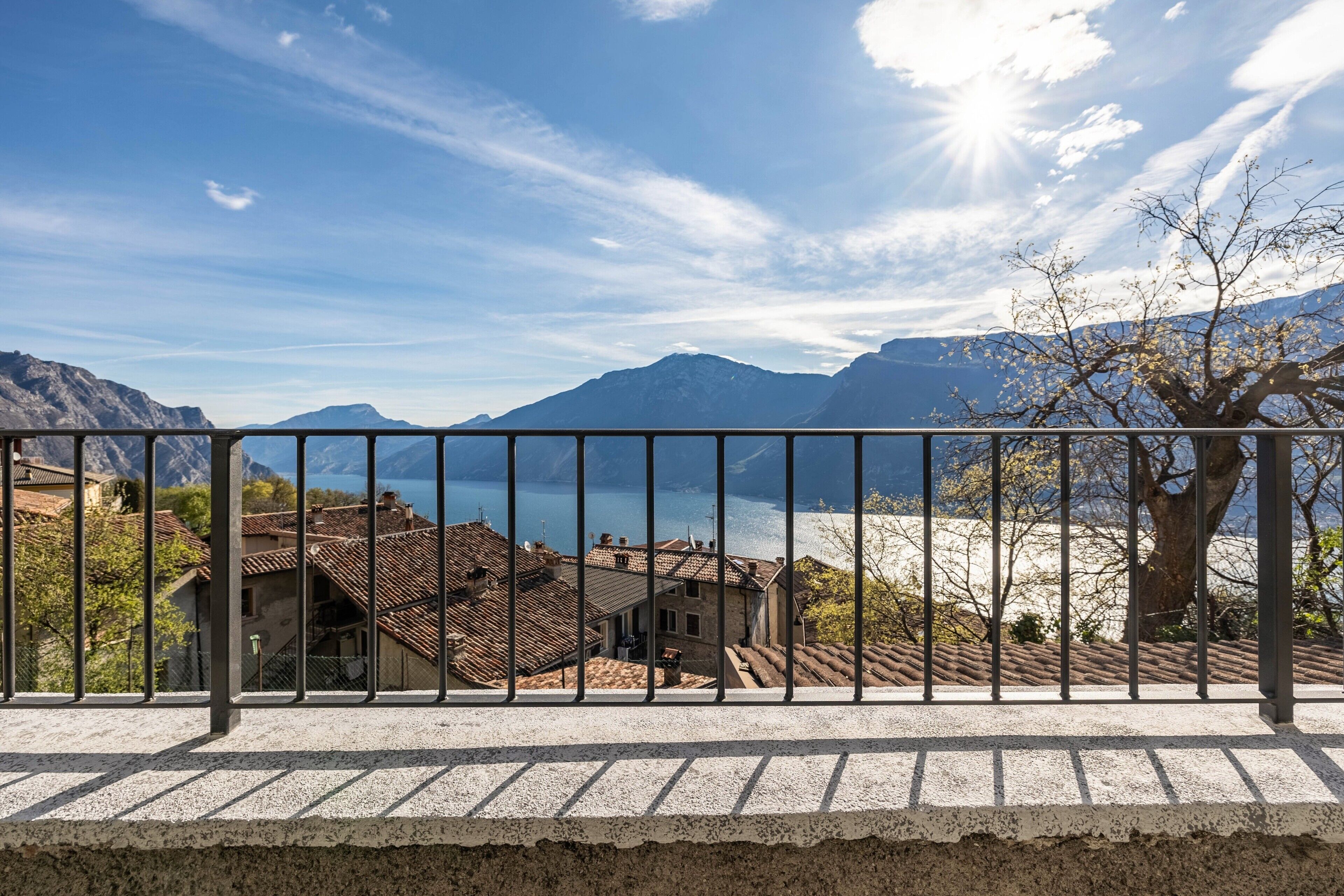 Un balcone con vista su un lago, montagne e un albero.