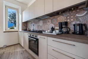 A kitchen with a gas stove, oven, and coffee makers. - Apartment 'Casa Bepi' with Lake View, Private Terrace and Wi-Fi (Tremosine sul Garda)