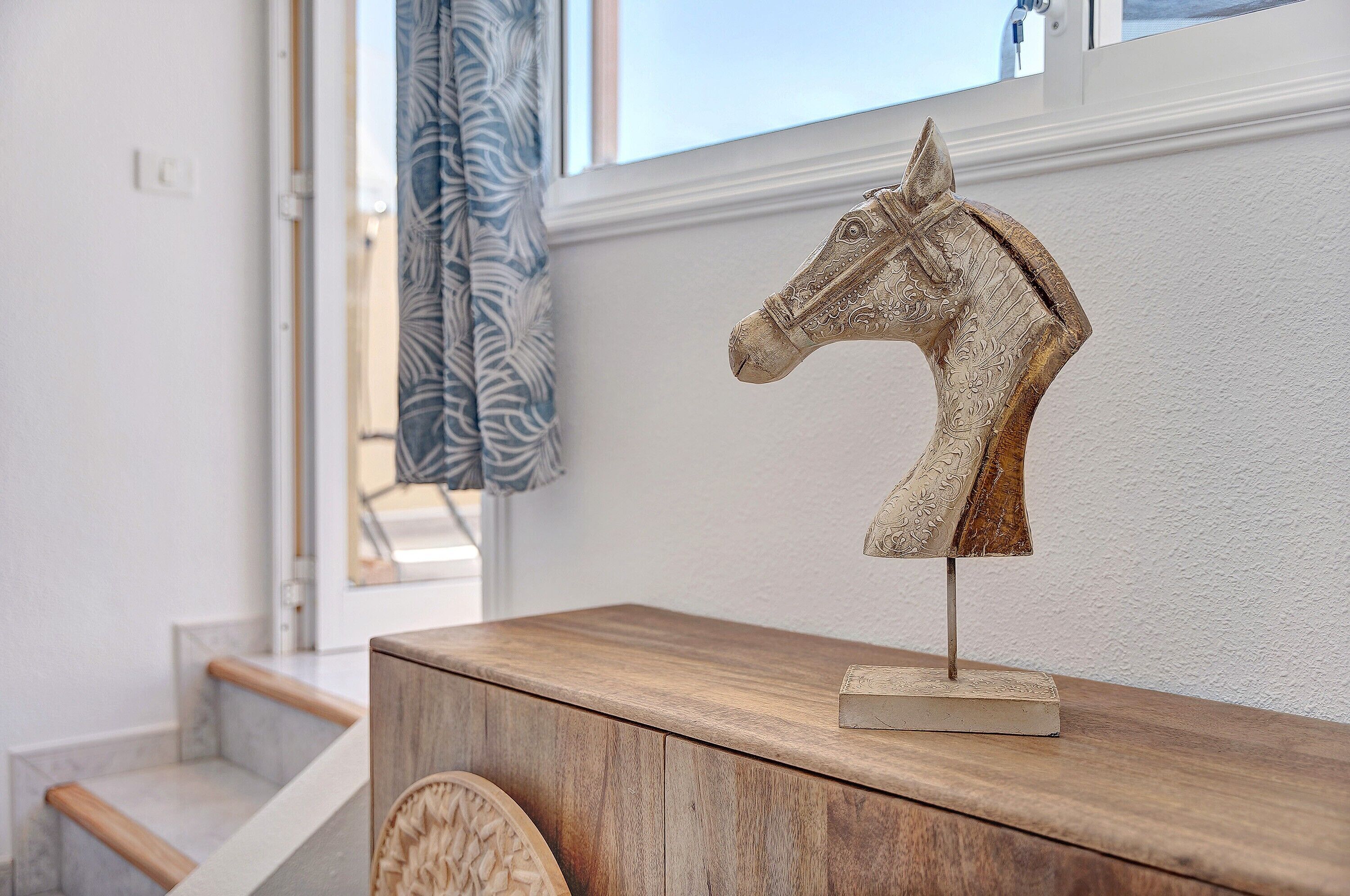 Un meuble en bois surmonté d’une sculpture décorative représentant une tête de cheval.
