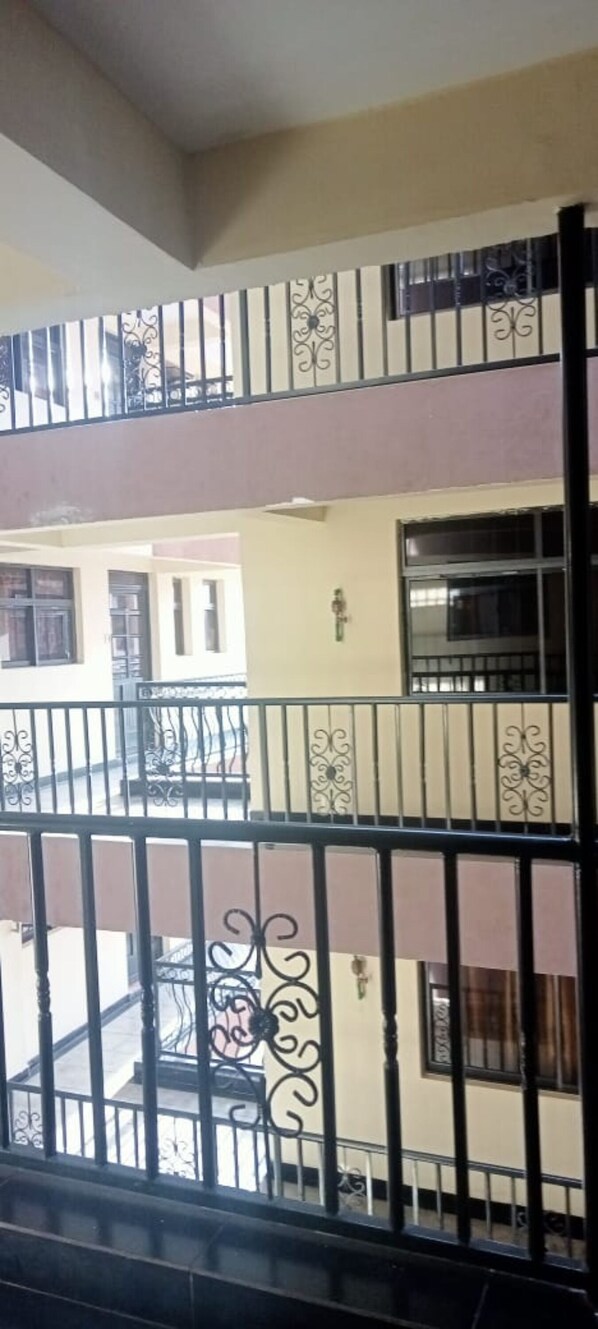 A multi-story building with balconies, a beige exterior, and black railings.