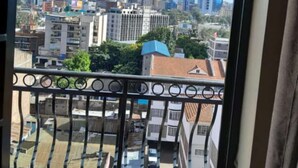 Varanda com vista para a cidade, incluindo vários edifícios e céu claro.