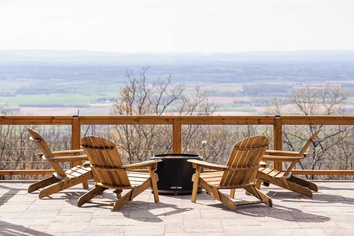 Una terraza de madera con sillas Adirondack y un brasero.