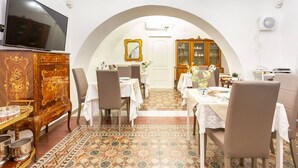 A dining area with a TV, wooden cabinet, and a tiled floor. - Terra d'Amuri Hotel (Catania)