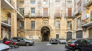 A narrow street with parked cars and a building with multiple balconies and windows. - Terra d'Amuri Hotel (Catania)